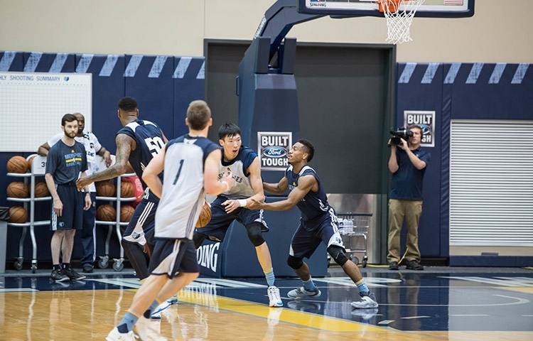 周琦在训练师的协助下进行核心力量训练，汗水湿透了衣背，每一滴汗水都见证着他为冲击NBA所付出的努力。