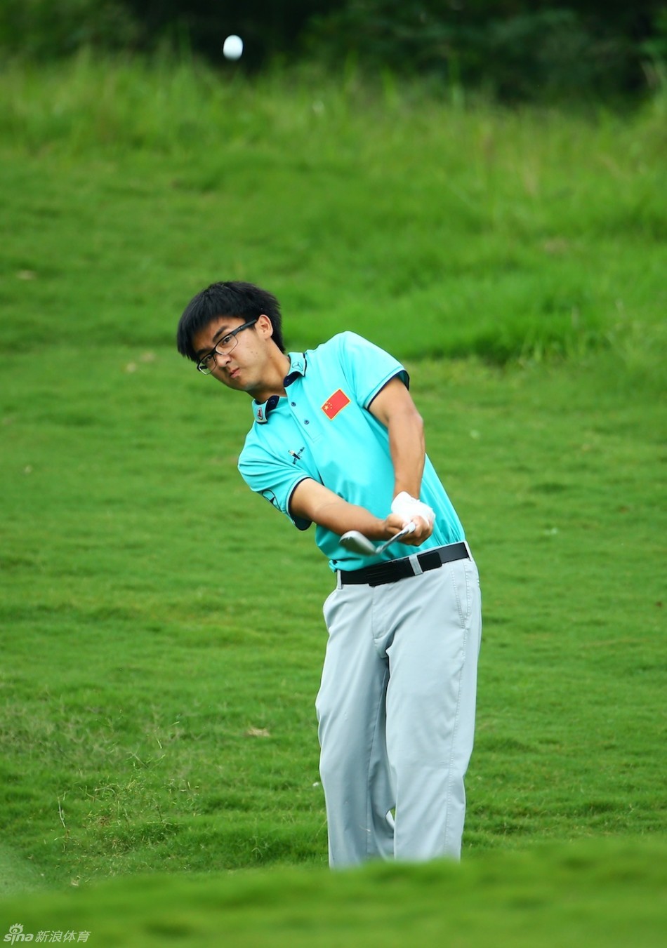 窦泽成在果岭边细致地观察地形与草纹,为下一杆精巧的切击做准备