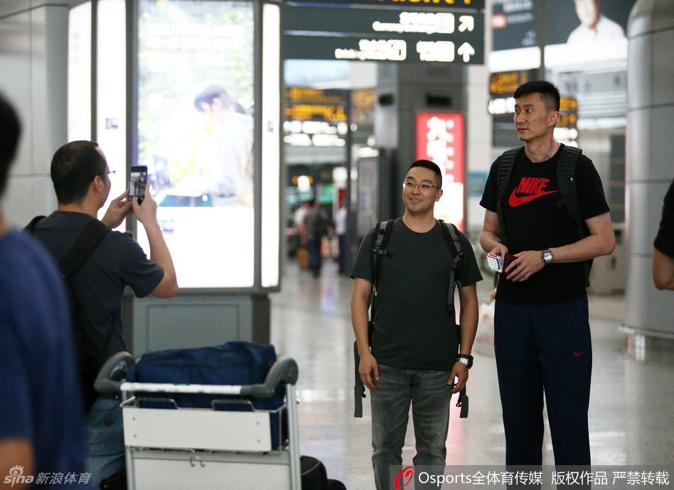 主教练杜锋与麾下两员小将高尚、董瀚麟在机场角落热聊，杜锋表情严肃似乎在叮嘱着什么，两人认真聆听，周围是熙攘的旅客，仿佛预示着老大哥正在传授新赛季的制胜秘诀。