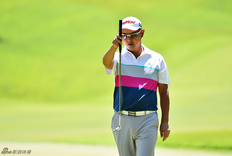 梁文冲面对果岭边长草中的棘手球位,正全神贯注地准备一次关键切杆,试图让球尽可能靠近洞杯。