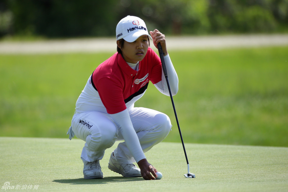 加拿大球星布鲁克·亨德森站在果岭环上，手搭凉棚远眺，评估下一杆的击球策略与果岭起伏。