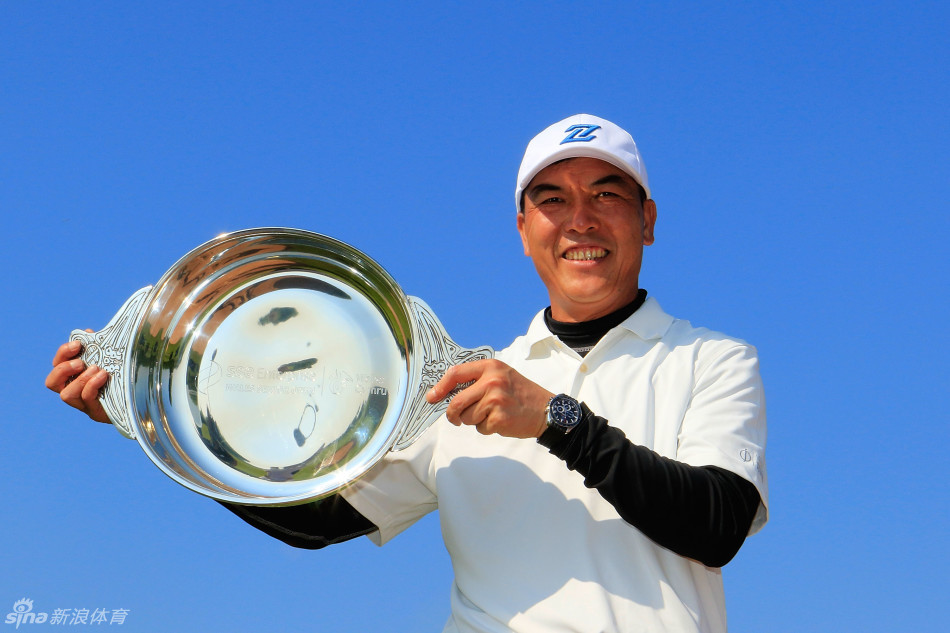 张连伟手捧冠军奖杯笑容满面，与身旁的赛事官员共同庆祝历史性夺冠时刻