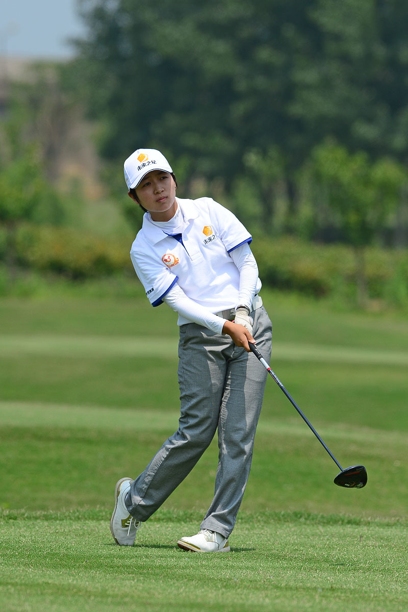 一名球员正在沙坑中处理困难球位，他身体微屈，目光锐利地聚焦于小球，手中的沙坑杆已做好准备，展现了高尔夫比赛中处理障碍时的专业与专注。