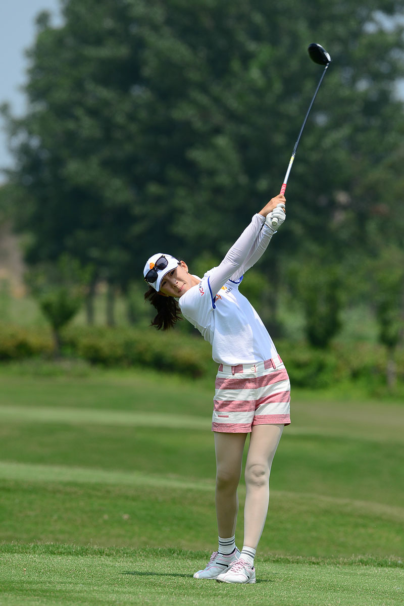 一位年轻球手正单膝跪在果岭边，聚精会神地观察推杆线路，他用手轻抚草皮感受坡度，展现了高尔夫运动中对细节的极致追求。