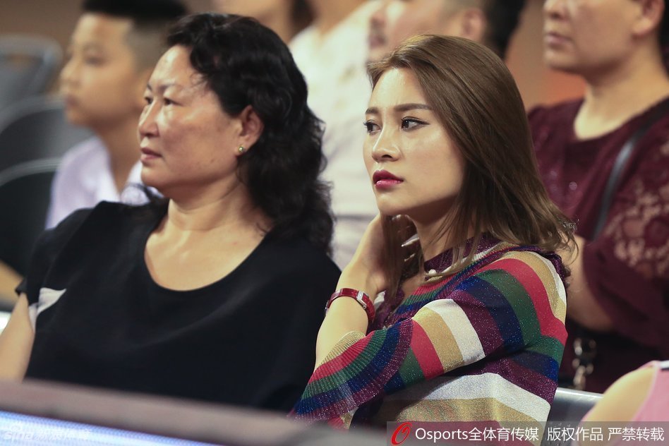 李根的母亲神情专注地望向赛场方向，眼中满是慈爱与骄傲，她专注地为儿子每一次攻防呐喊助威。