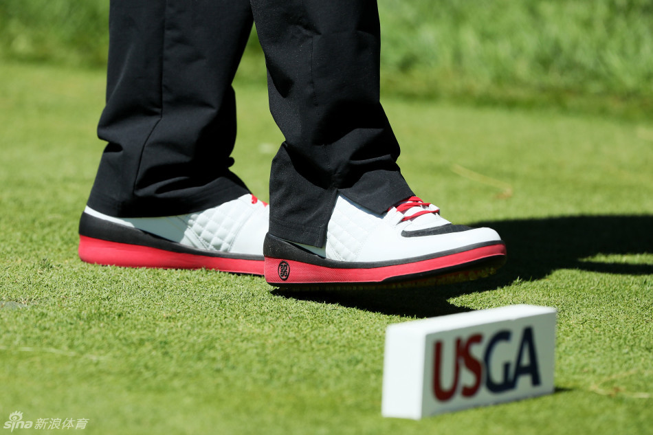 奥克芒俱乐部的园艺师正单膝跪地，手持专业工具，全神贯注地对果岭边缘进行精细的修剪与维护。