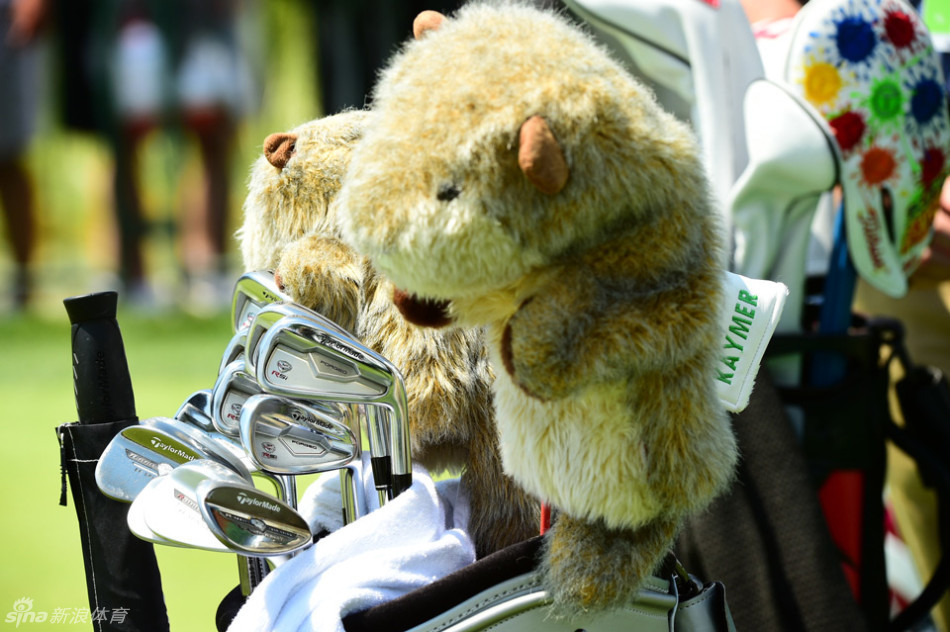 高尔夫球手在比赛中从容走过小桥,倒影与绿意构成一幅宁静的球场画卷