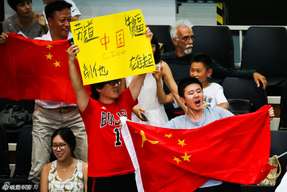 看台上的中国球迷们挥舞着五星红旗，脸上画着国旗图案，神情专注地为场上的每一次精彩表现呐喊助威