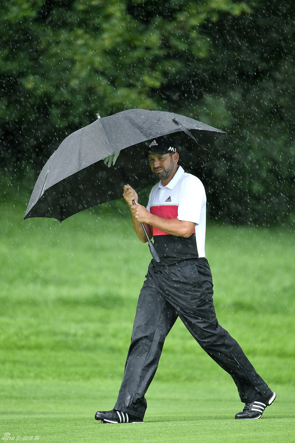 西班牙名将加西亚在雨中撑起雨伞，眉头微蹙，专注地审视着前方的比赛线路