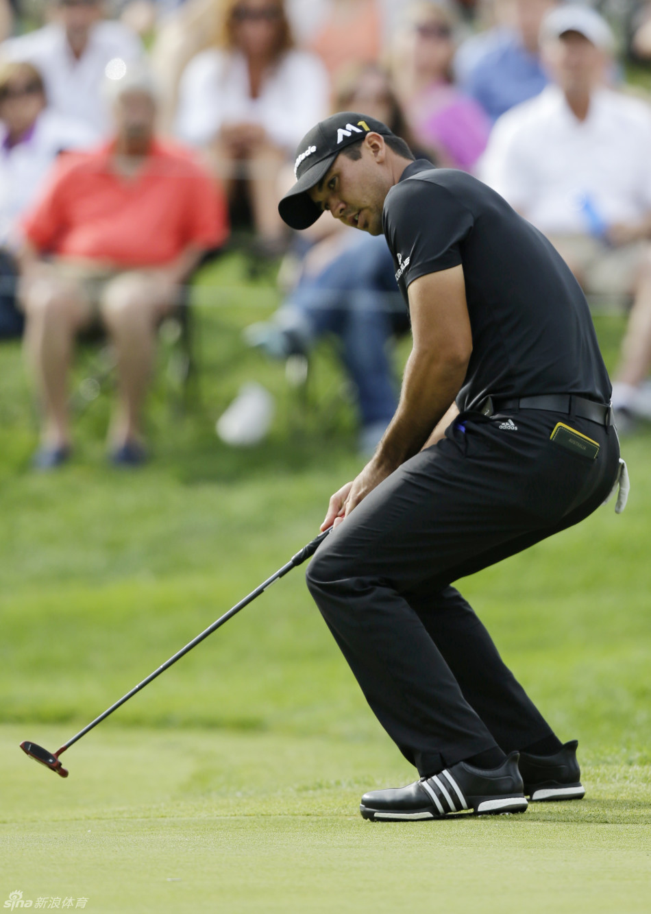 简森·戴伊屏息凝神，在果岭上仔细观察球的滚动路线，寻找一击制胜的机会。