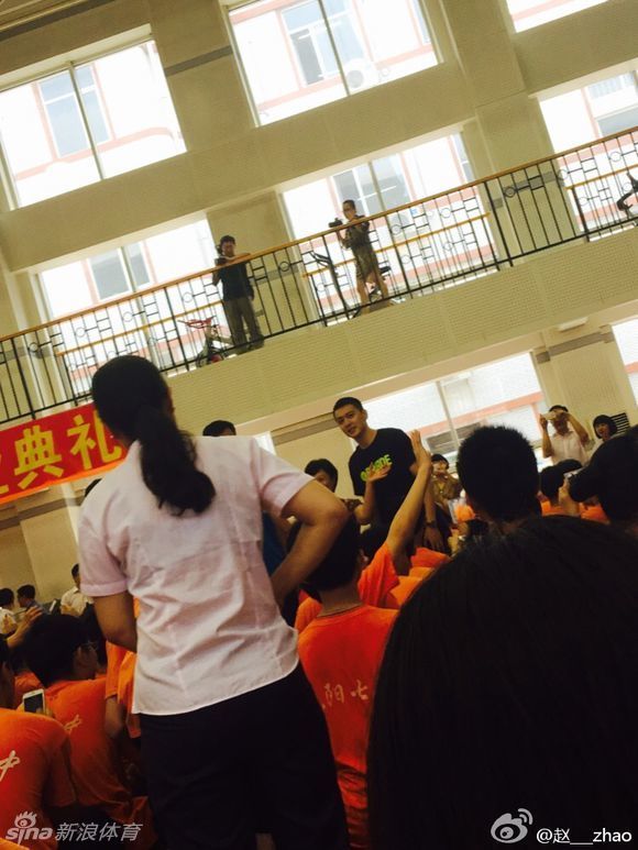 身穿笔挺衬衫的杨鸣，正在台上拿着话筒进行发言，他神情专注，眼神中透露出对篮球事业的坚定与热爱。