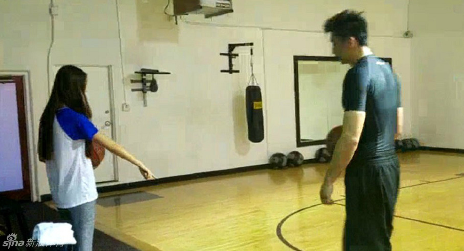 妻子做出夸张的防守姿势试图封盖丈夫的投篮，眼神中充满挑衅与爱意