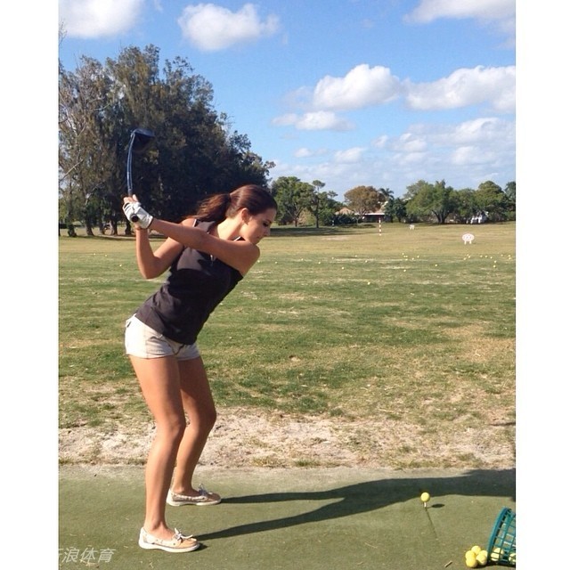 玛琳娜完成挥杆后优雅收杆，笑容灿烂如佛罗里达的阳光，身后球场绿意盎然，尽显运动后的畅快