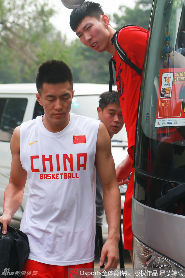 易建联坐在场边休息，目光投向远处正在投篮的年轻队友们，脸上浮现出轻松而欣慰的笑容，仿佛在说：接下来就看你们了。