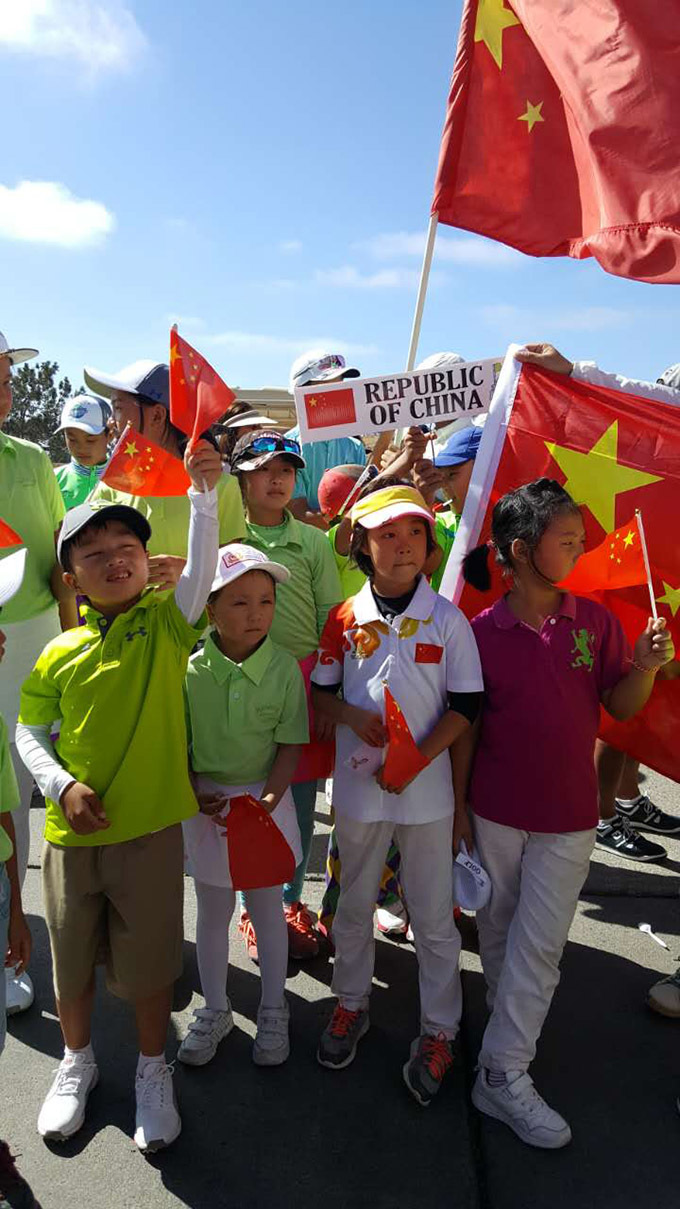 赛事主办方代表正在开幕式上致辞,背后大屏幕展示着赛事标志,台下是静静聆听的各国选手与家长。