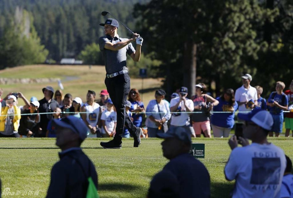 库里正俯身为一位小球迷签名，他神情温和而认真，孩子仰望着他，眼中充满了崇拜与喜悦。