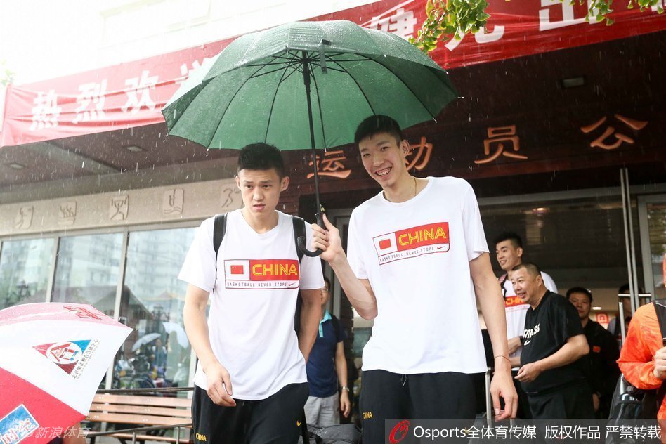 主帅宫鲁鸣在领队的撑伞护送下准备上车，这位功勋教头神情严肃，他将带领这支年轻的队伍去感受世界最高水平的篮球对抗。