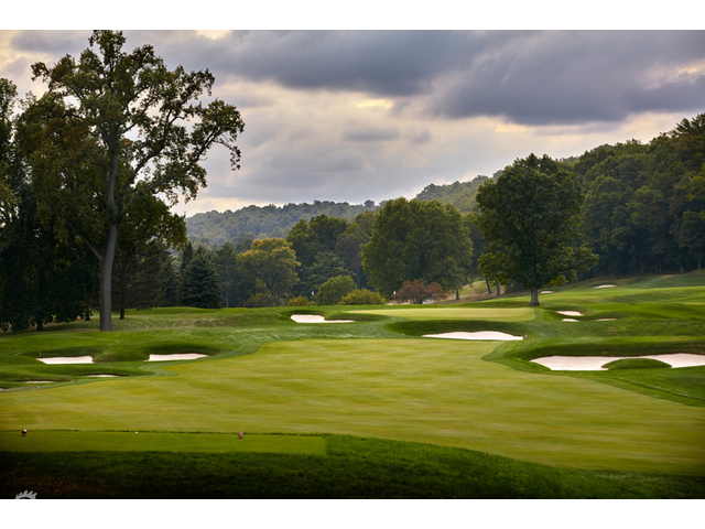 锦标赛现场，观众聚集在果岭旁的山坡上，屏息凝神观看球手应对关键推杆。