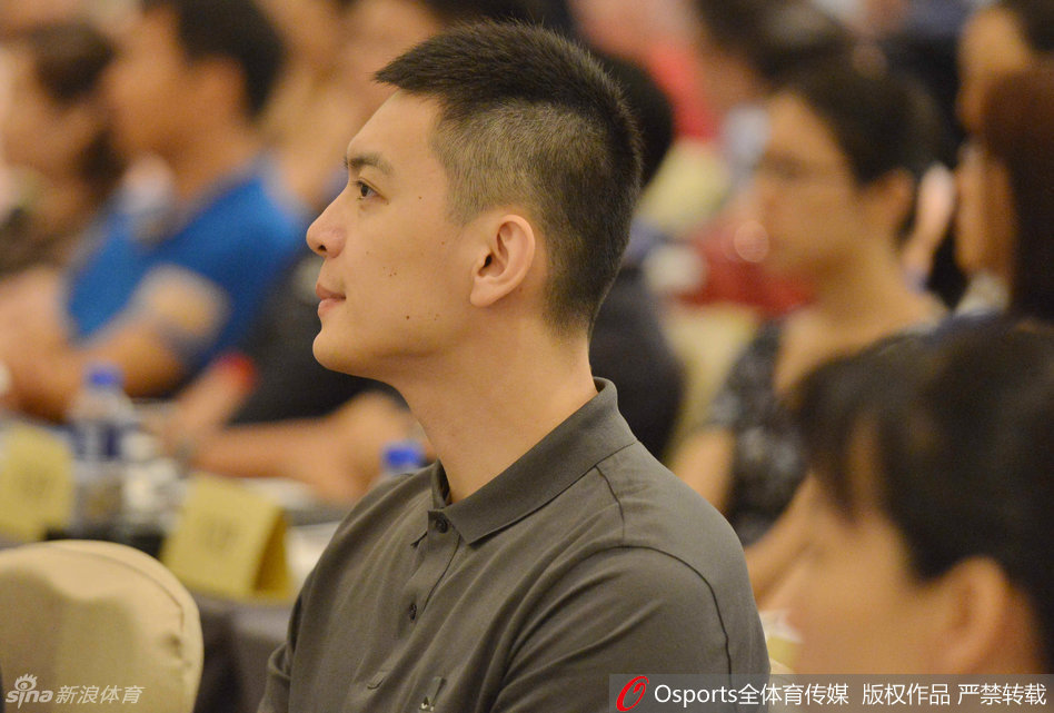 杨鸣在活动现场与学生互动，手指轻点桌面，神情专注地倾听孩子的提问。