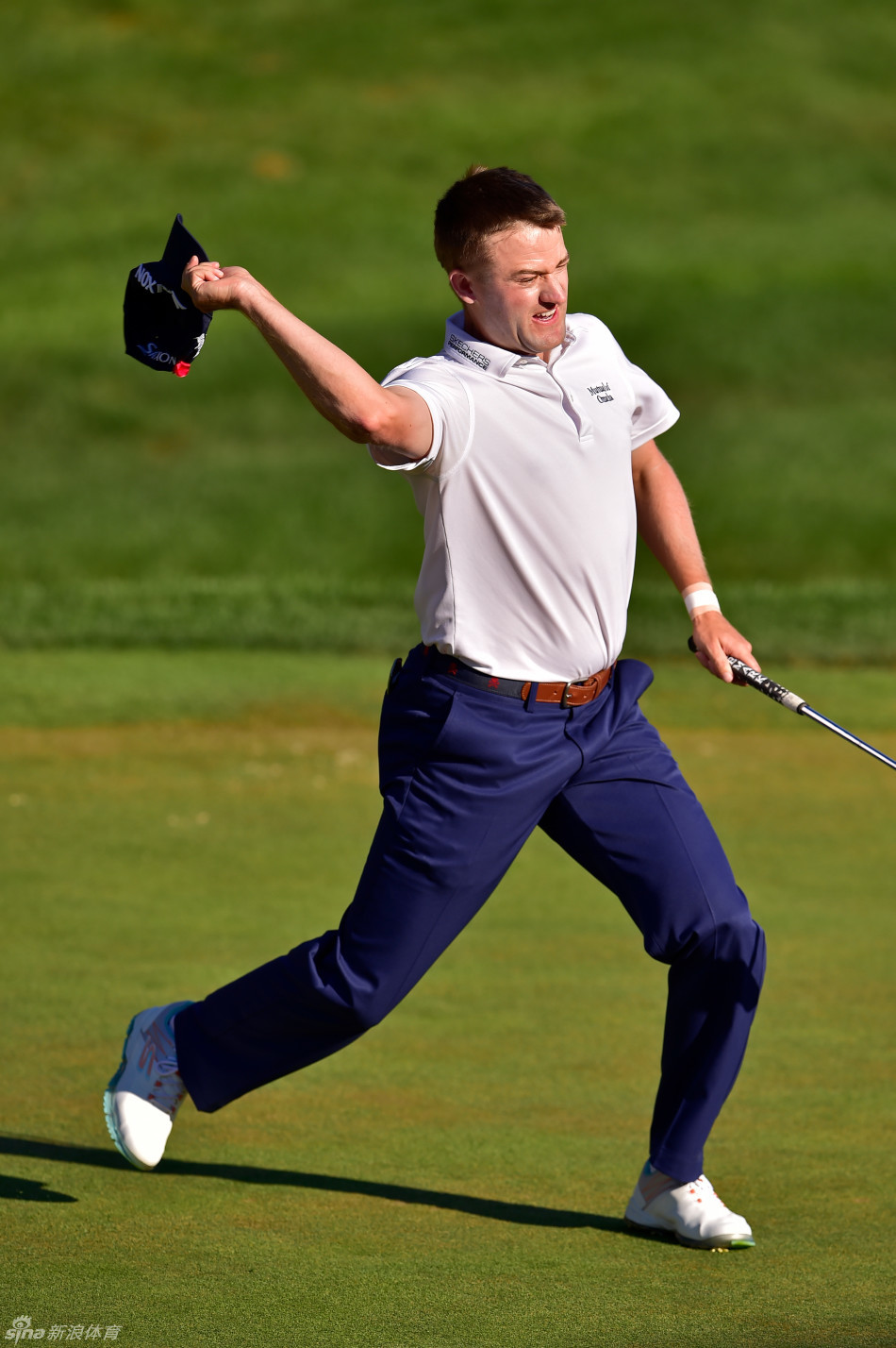 夺冠后狂喜的诺克斯奋力将帽子抛向空中，身后是TPC河流高地第十八洞果岭和沸腾的观众。