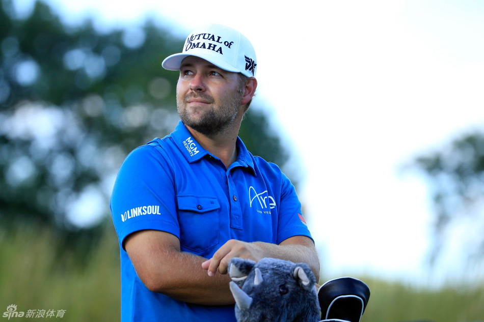 赖安·摩尔在暮色笼罩的果岭上专注研判推杆线路，身旁巨大的电子记分牌成为唯一光源。