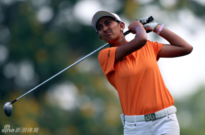 印度球手阿迪蒂-阿肖克在果岭边专注推杆，阳光将她自信的身影拉长，绿色草坪与蔚蓝天空构成壮丽背景