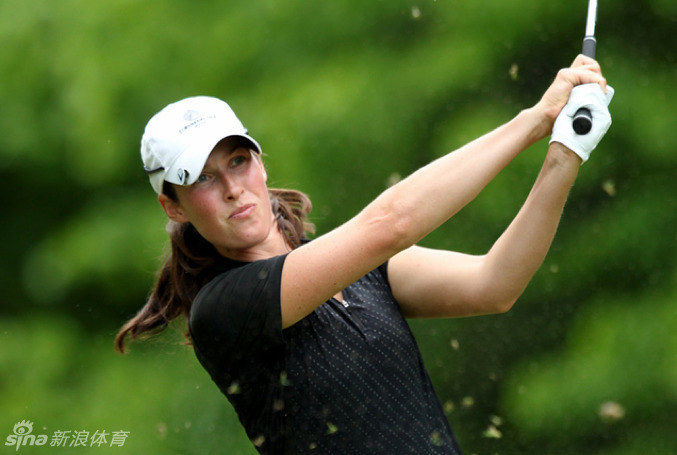 以色列球员莉蒂希亚-贝克优雅完成开球动作，白色球帽下眼神坚定，球杆划出完美弧线