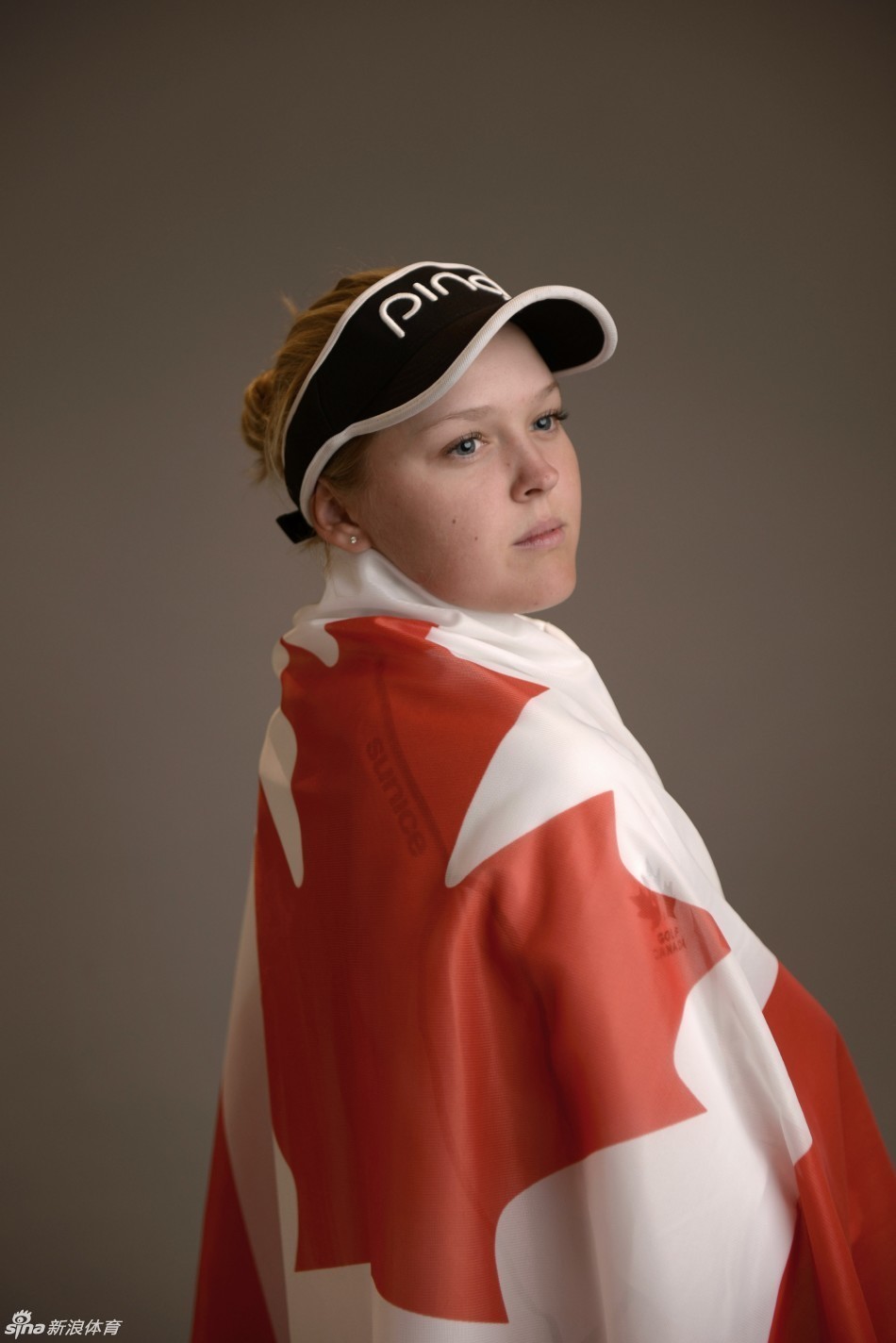 绿茵赛场上一名女球员完成优雅收杆，背景是广阔球场与蓝天白云