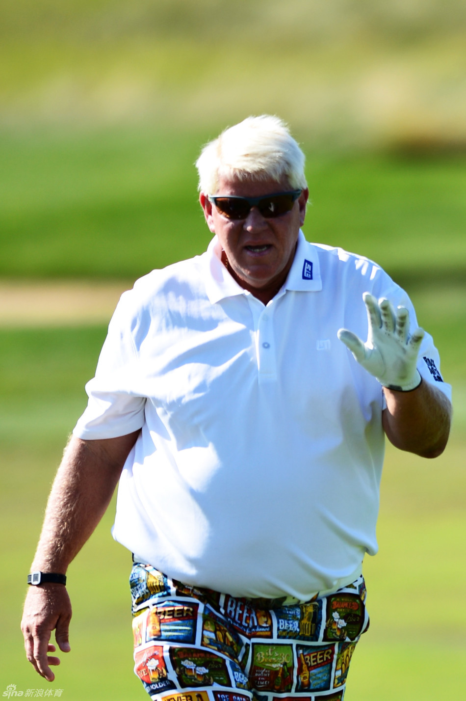 球迷悠闲地卧在赛场坡地上观看比赛，远处‘白老虎’李-维斯特伍德正在挥杆