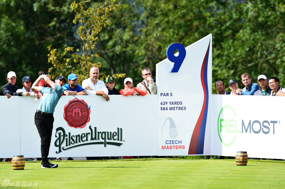 彼得森俯身专注于一个关键的推击，他的球童在一旁静静协助，果岭背景是典型的欧式球场风景