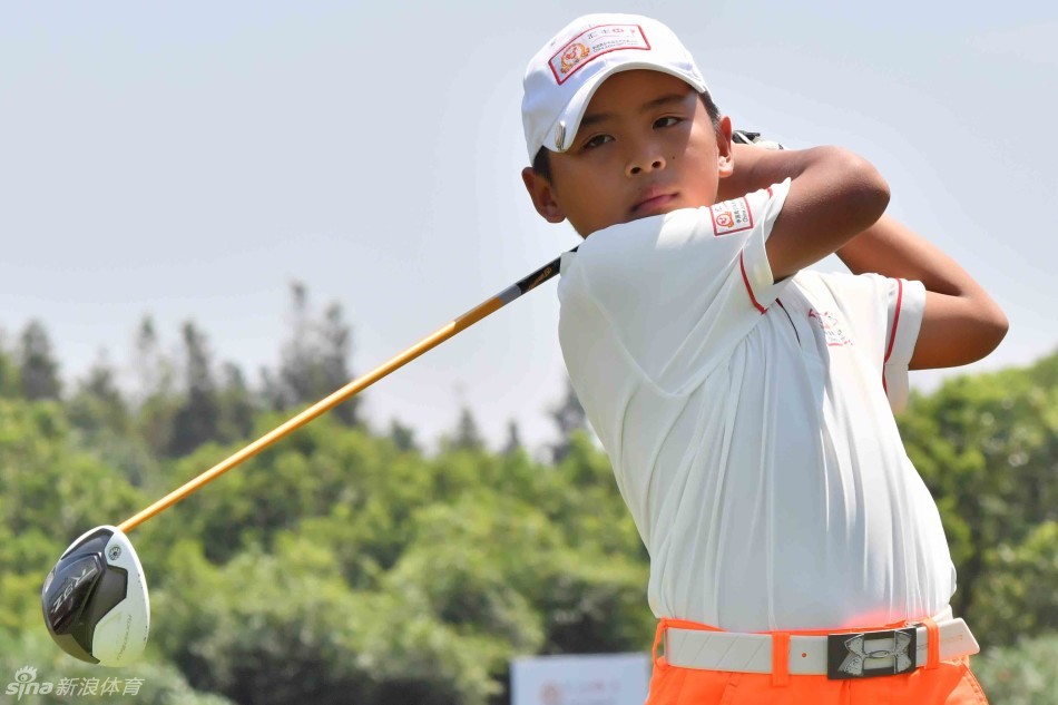 小球员在果岭边进行精准切杆,目光紧随小白球划出的抛物线落向球洞。