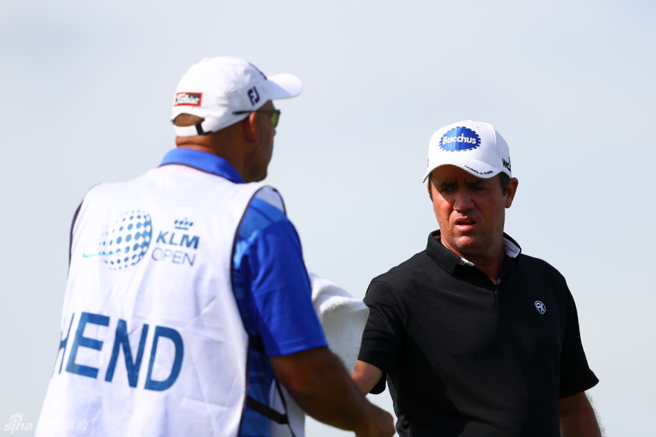 海顿-克鲁格与球童在比赛中密切交流，两人手势坚定，正深入分析下一杆的策略与风向
