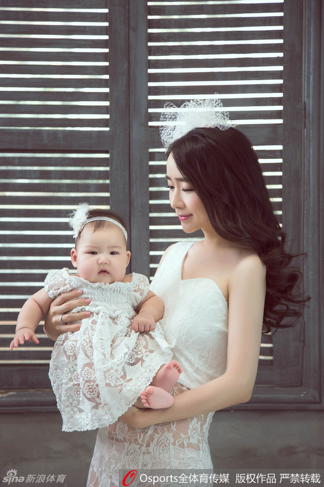 赵丹丹轻抚女儿的小手，眼神温柔似水，母女俩的亲密互动在镜头下显得格外唯美，辣妈的好身材在简约装扮下一览无余。