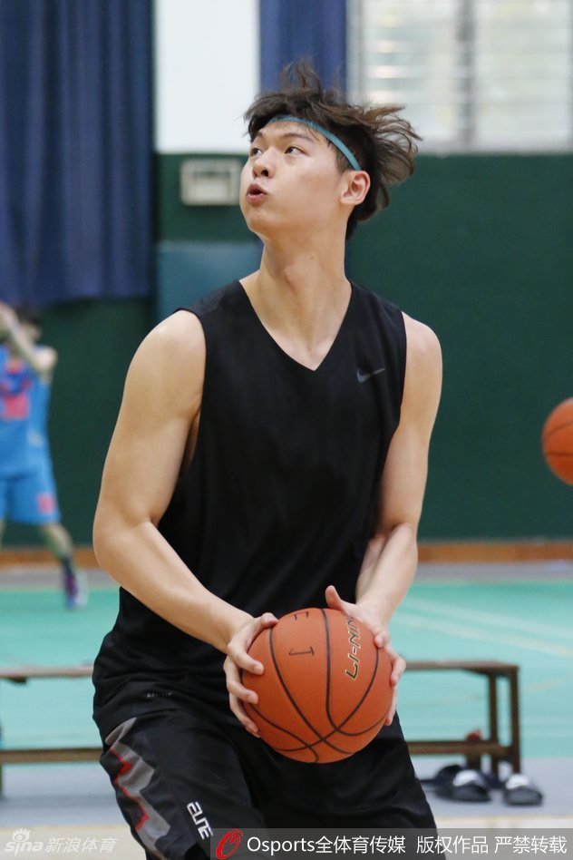 训练馆里王哲林与张德贵指导低头交流，教练手指战术板比划着跑位路线，大王认真倾听不时点头，身旁朱世龙和普拉达也在关注讨论。