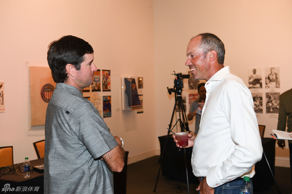 巴巴-沃森与马特-库查尔在背景板前并肩而立，亲密交谈，两人之间轻松融洽的氛围尽显好友情谊。