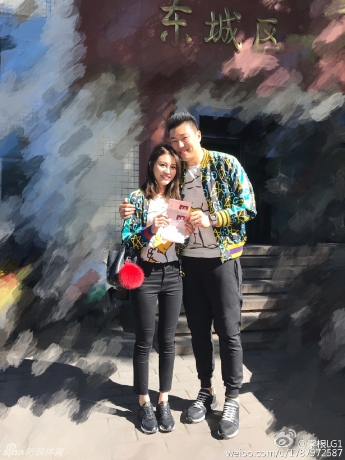 李根身着休闲运动装，轻松地将满脸幸福笑容的妻子高高扛起，妻子在空中挥舞着双手，两人的互动充满了童趣与甜蜜。