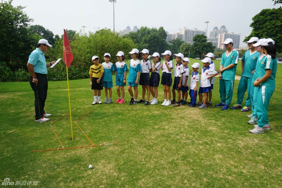孩子们围坐在教练身旁，全神贯注地聆听高尔夫挥杆技巧讲解，眼中闪烁着好奇与求知的光芒