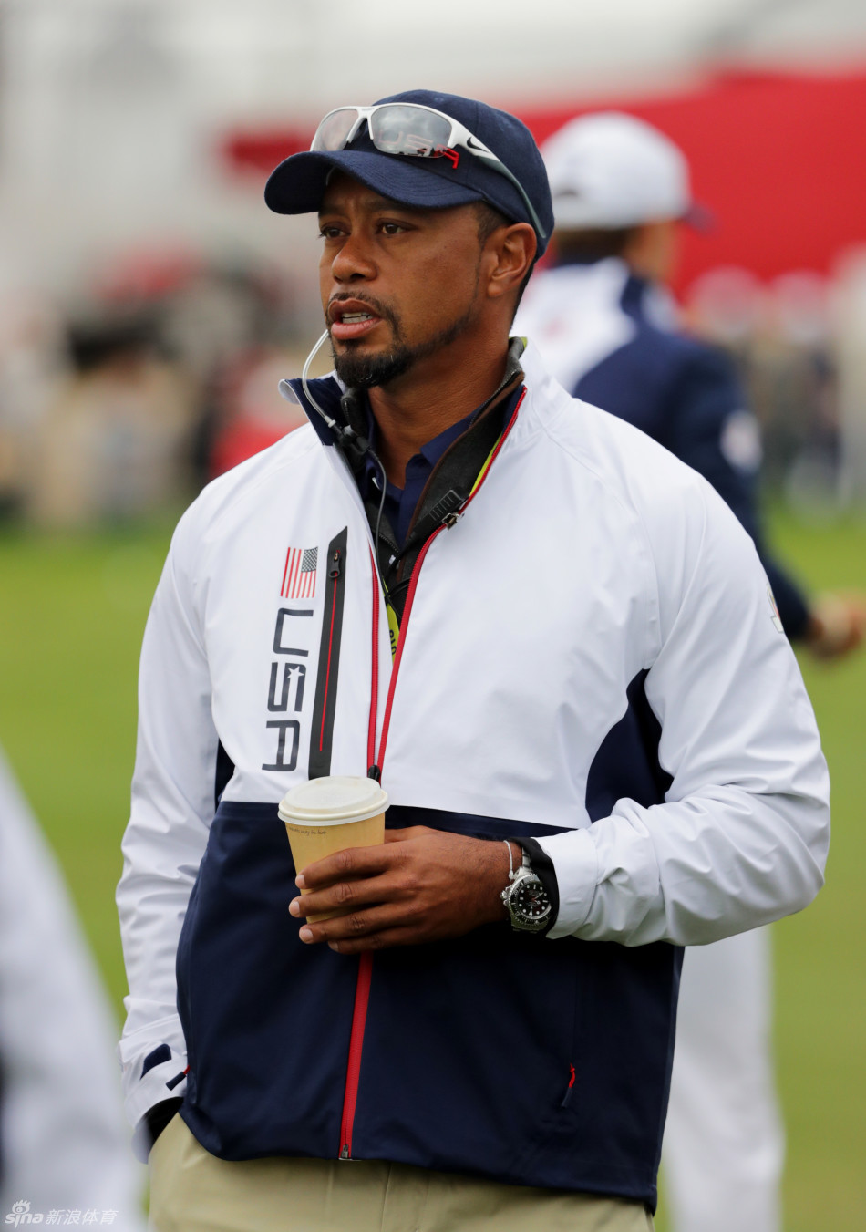 伍兹在赛场边与团队成员轻松交谈,众人脸上洋溢着笑容,团队气氛和谐紧密