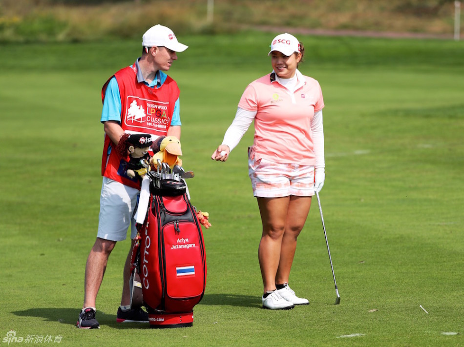 阿瑞雅与球童并肩观察球场，共同商讨下一杆的策略与路线