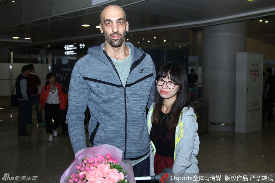 阿巴斯在抵达仪式上与江苏同曦俱乐部人员交流，背景是球队的训练基地，金陵秋日的阳光下，一段全新的篮球冒险就此开启。