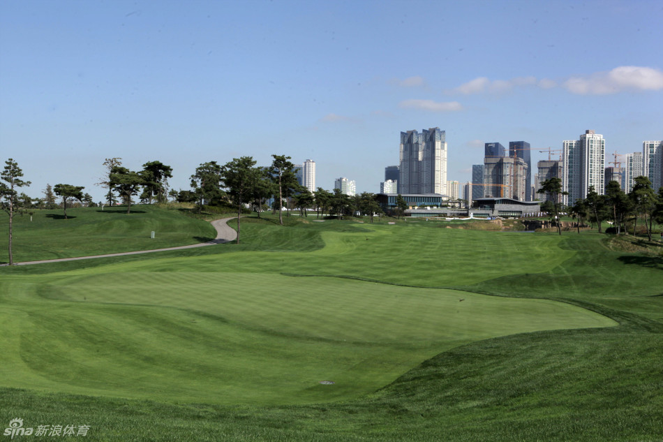 亚太业余锦标赛赛事旗帜与韩国杰克尼克劳斯高尔夫球会会所建筑在蓝天白云下交相辉映，象征着高球传统与新兴力量的汇聚。