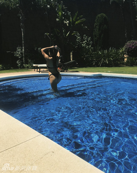 阳光洒落在泳池边,一位女性身着时尚泳装开怀大笑,水珠在阳光下晶莹剔透,洋溢着无忧无虑的快乐