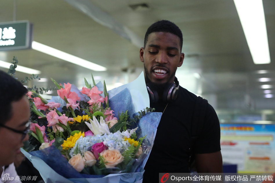 走出机场通道的汤普森面对接机人群，眼神中带着旅途的疲惫与对新征程的渴望，身后巨大的行李箱装满了他在NBA八年的回忆与荣誉。