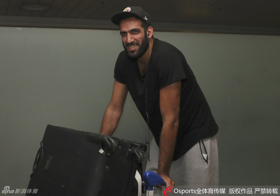 哈达迪在机场与热情的四川球迷互动，他面带笑容侧耳倾听球迷的问候，身后的落地窗外是成都的天空，画面里流淌着跨越国界的真挚情感。