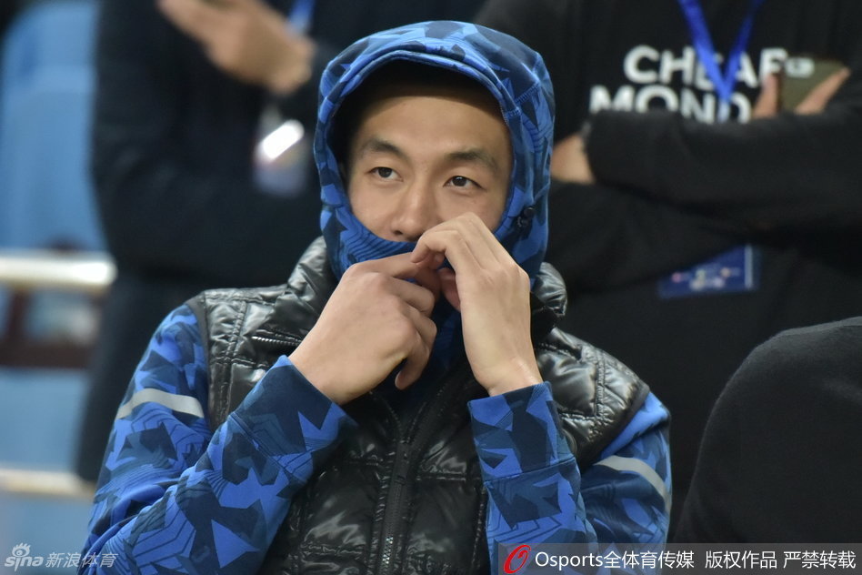 郭艾伦彻底将自己埋进羽绒服里，只露出半张脸和手中的棒棒糖，他悠然望向远方，仿佛在享受这个难得的、没有比赛压力的宁静时刻。