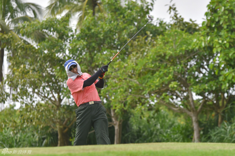 观众视角下，一位高尔夫球手在宽阔的球道上挥杆开球，一号木杆面与小球碰撞的瞬间充满力量，画面动感十足