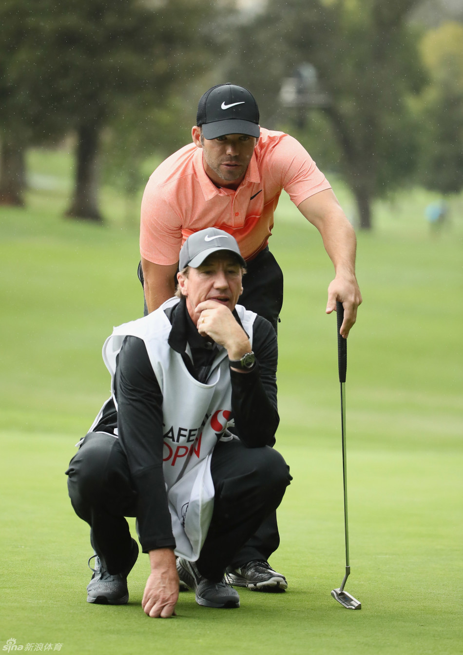 保罗·卡西与球童一同蹲在果岭边仔细观察推杆线路,专注商讨制胜策略。