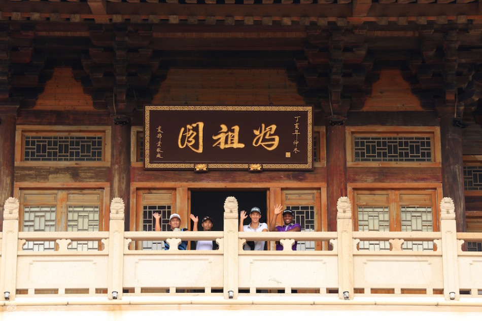 参与者在妈祖祖祠内双手合十，闭目虔诚祈福，阳光透过门廊洒落，氛围宁静而祥和。