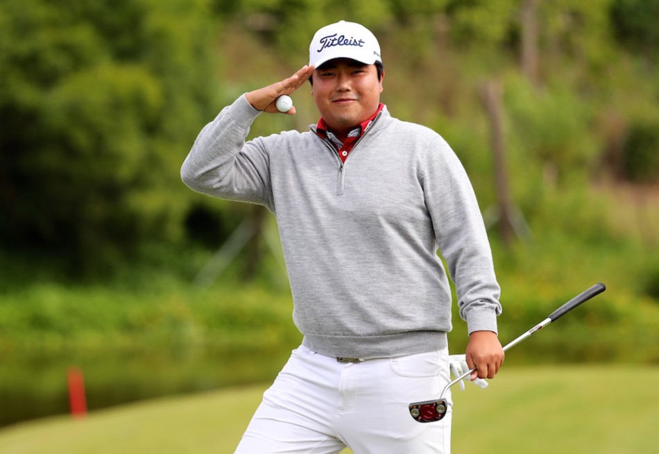 韩国选手金兑祐在果岭旁优雅地向观众致意,脸上洋溢着自信与从容的笑容。