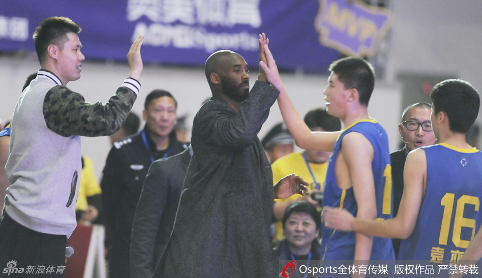 央视名嘴于嘉在场地中央采访两位篮球名宿，科比谈笑风生，贺天举侧耳倾听，三人相谈甚欢。